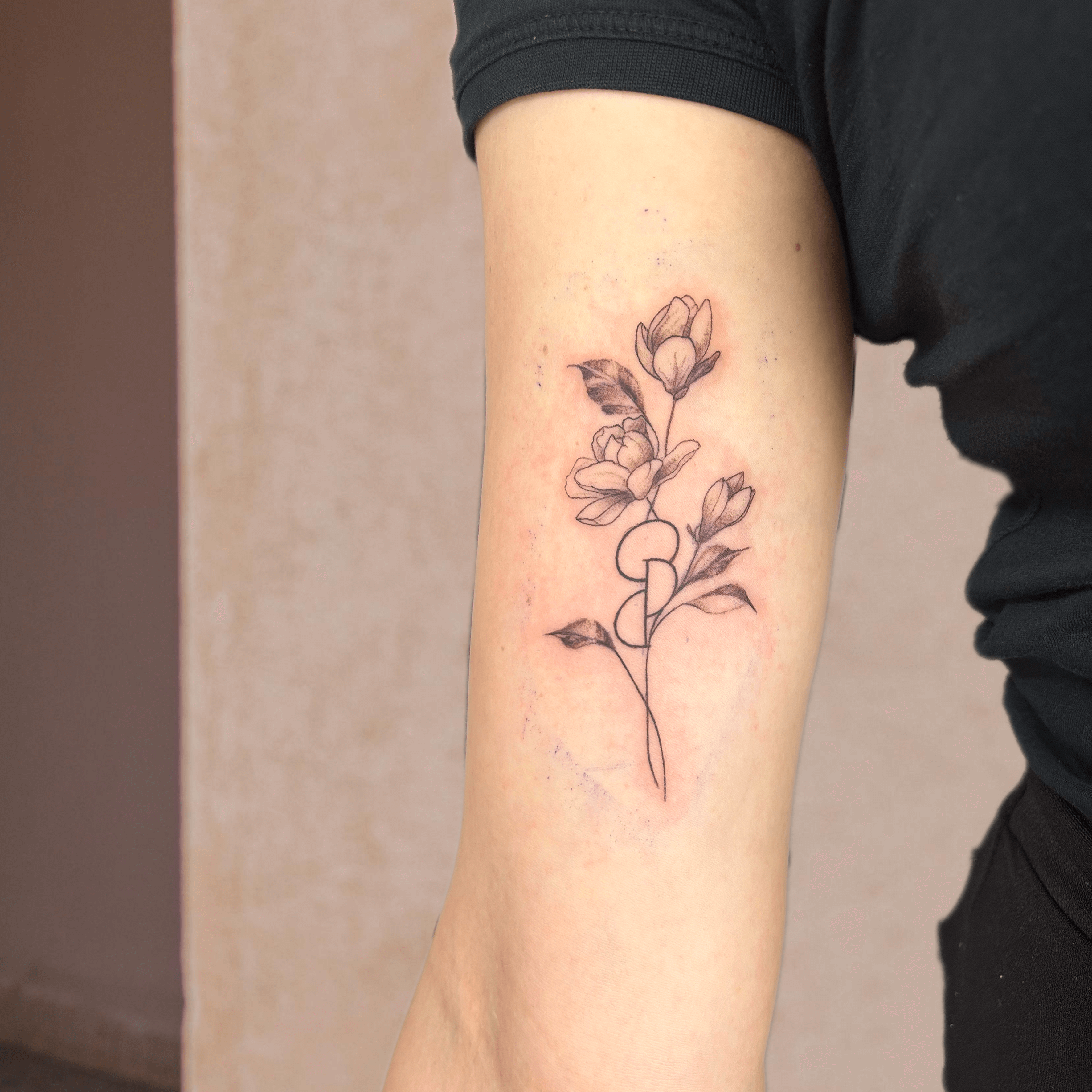 Tattoo mit floralen Motiven, das auf dem Unterarm platziert ist, mit geschwungenen Linien und Blüten.