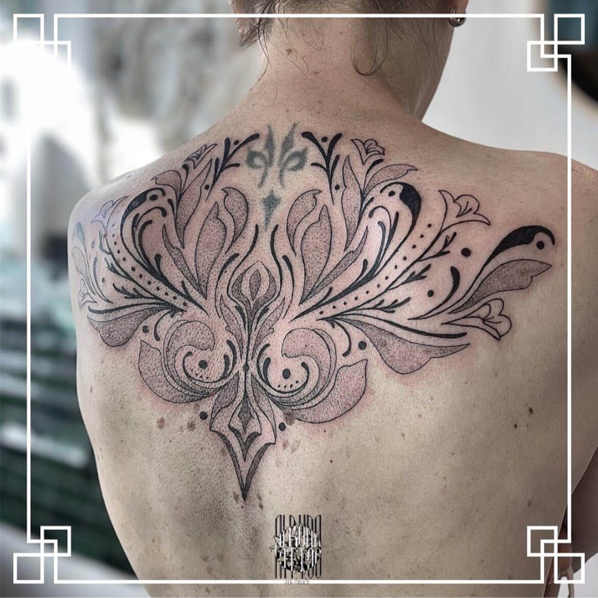 Großes Mandala-Tattoo, das den oberen Rücken ziert, mit detaillierten Mustern und Linien.