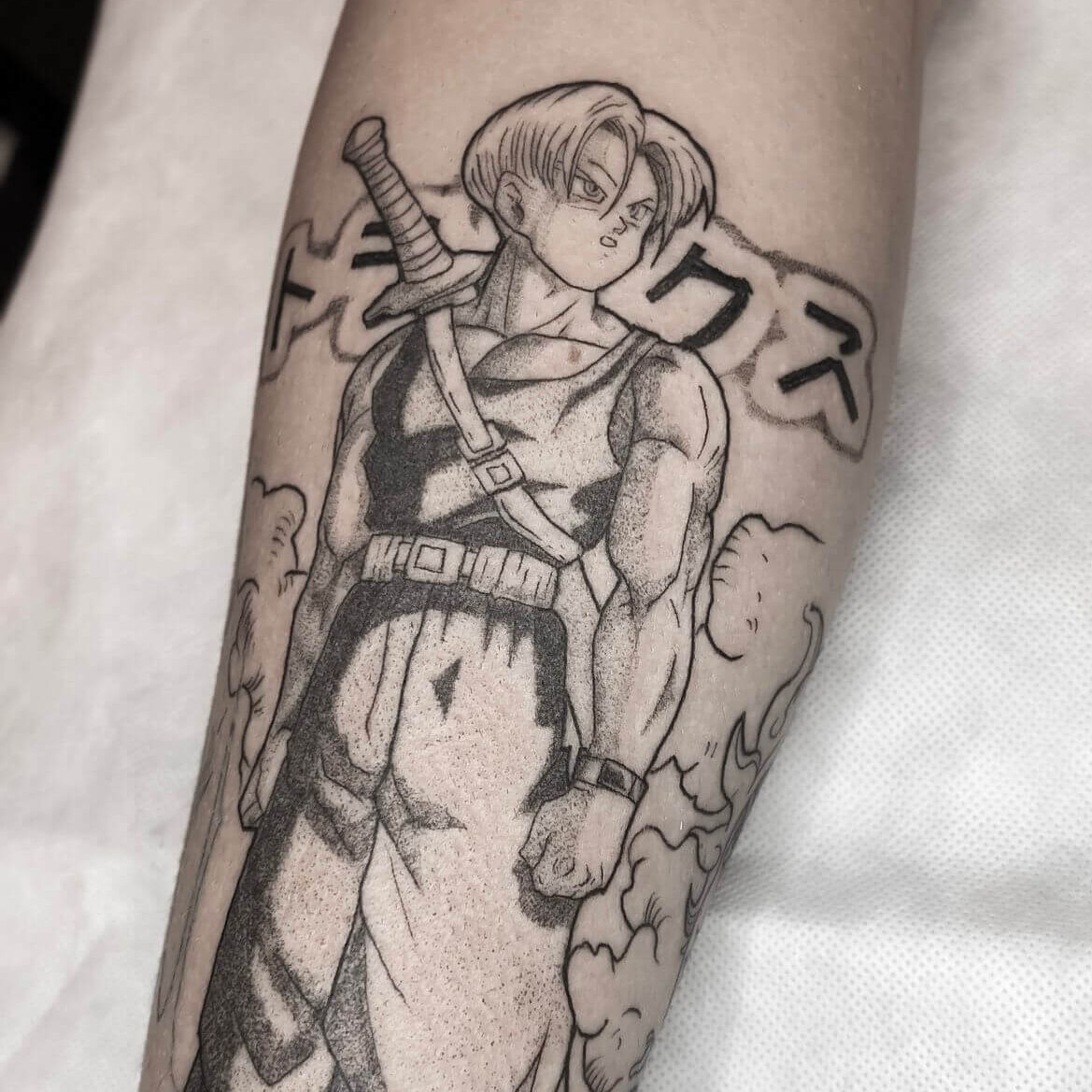 Tattoo des Anime Charakters Trunks aus dem Anime Dragonball mit einem Schwert, der in einer kraftvollen Pose steht, umgeben von Wolken.