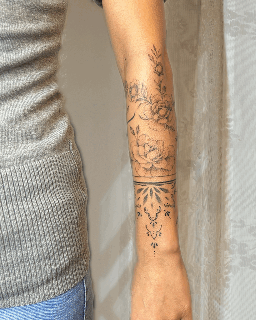 Florales Tattoo am Unterarm – feine Rosenranken mit Blättern, kombiniert mit geometrisch-ornamentalem Muster am Handgelenk.