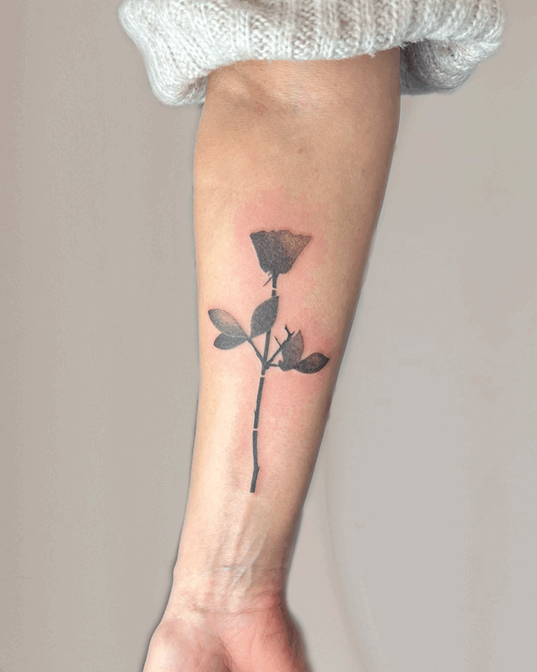 Minimalistisches Rosentattoo am Unterarm – schwarze Rose mit Blättern und filigranem Stiel in schlichter, moderner Gestaltung, depreche mode